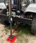 Seven Sparta off-road base stand for Hi-Lift jack with black steel post and red base plate on Jeep front.