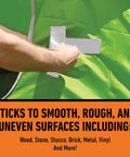 Applying Beast Tough Heavy Duty White Duct Tape 1.88 Inch Wide By 10 Yards Long Pack Of 6 on a green uneven surface, showing versatility.