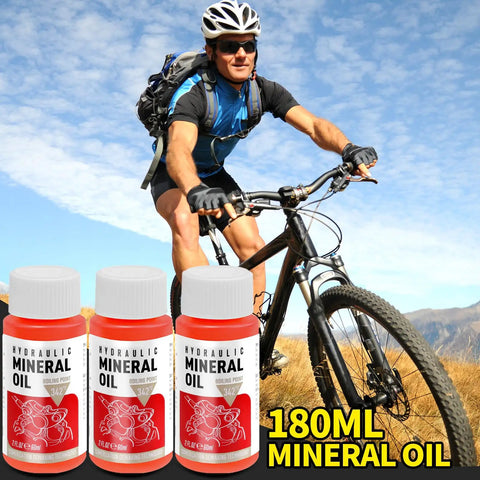 Cyclist on mountain bike with bottles of 180ml hydraulic mineral oil for disc brake bleed kit.