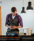 Man in workshop using phone under LED pendant lights with energy-saving message on overlay.