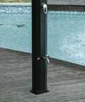 Close-up of black freestanding 7Ft Outdoor Solar Heated Shower with 360 Degree Rotating Head by a pool, showcasing foot shower faucet.