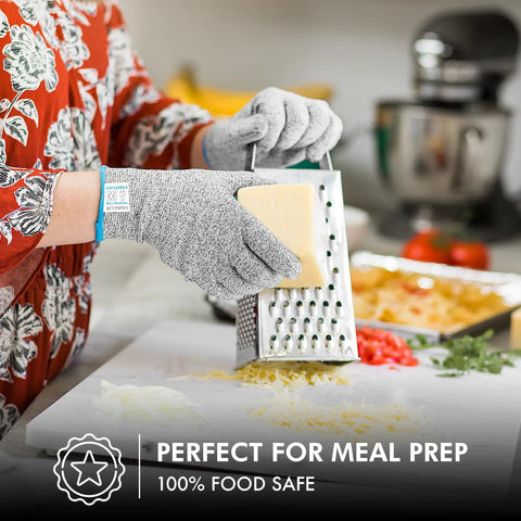 Person using Ultra Safe Cut Resistant Gloves Level 5 Protection For Kitchen Prep Meat Handling Filleting Shucking Slicing Carving Large XL Size Heavy Duty Food Prep Hand Guard while grating cheese in a kitchen.