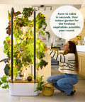 Indoor Vertical Hydroponics Kit For Home Gardening With LED Grow Lights Grows 30 Non GMO Plants Herbs And Vegetables In Just 2 Sq Ft No Fuss Energy Efficient Sunrise And Sunset Modes Smart Garden System with woman tending plants in kitchen.