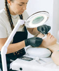 LightView Pro Magnifying Glass With Light And Stand used in facial at salon, showcasing hands-free lamp and adjustable arm.