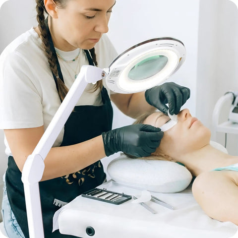 LightView Pro Magnifying Glass With Light And Stand used in facial at salon, showcasing hands-free lamp and adjustable arm.