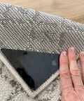 Hand applying No Slip Rug Grippers 12 Pack Carpet Stickers For Area Rugs Double Sided Tape For Hardwood Floors And Tile Floors No Damage Anti Slip Fasteners Stop Rug Pad Curling And Slipping under a rug corner.