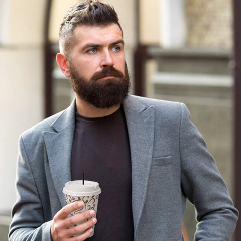 Man holding coffee cup with Skinny Black Plastic Sip Stirrer Straws for Coffee and Cocktails in a gray suit outside.