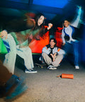 Group of friends enjoying music outdoors with the Ultimate Field 1 Waterproof Portable Bluetooth Speaker on the ground, colorful lights.