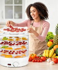 Heavy Duty Electric Food Dehydrator With Five Clear Trays And Adjustable Heat Zones For Zero Fuss Drying Of Fruit Meat Jerky And Custom Pet Treats Perfect For Family Dinners And Weekend Meal Prep in use with sliced fruits and jerky.
