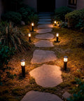 Evening scene showcasing 4 Pack Low Voltage Pathway Lights Dope 3W LED Outdoor Landscape Lighting 120 Lumen 3000K along a stone path.