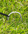 Metal stake securing Pop Up Baseball Batting Cage With Portable Fiberglass Frame And Polyester Netting on grass