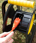Jobsite Ready Beefy Cord Reel With 4 Grounded Outlets Black And Yellow Holds 50 Ft Of 12 Gauge 70 Ft Of 14 Gauge Or 90 Ft Of 16 Gauge Circuit Breaker Protected Extension Reel For Powering Multiple Tools in use outdoors