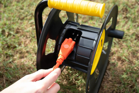 Jobsite Ready Beefy Cord Reel With 4 Grounded Outlets Black And Yellow Holds 50 Ft Of 12 Gauge 70 Ft Of 14 Gauge Or 90 Ft Of 16 Gauge Circuit Breaker Protected Extension Reel For Powering Multiple Tools in use outdoors