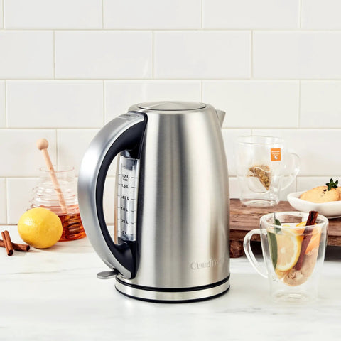 Stainless Steel Electric Kettle 1.7 Liter Cordless Design With 1500 Watt Power boiling water beside tea and lemon on counter.