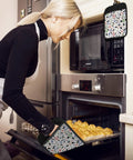 Woman baking with Funny Mahjong Inspired Pot Holders For Kitchen in use, oven mitts protecting hands, quirky kitchen decor.