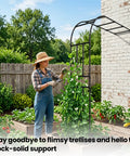 Person gardening with Half Garden Arch Trellis For Climbing Plants Outdoor, Wall Mounted Beefy Black Metal Arbor on brick wall.