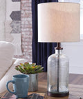 Modern Farmhouse Seeded Glass Table Lamp in Bronze Finish, 22.5 Inch Tall on a wooden table beside a mug and plant