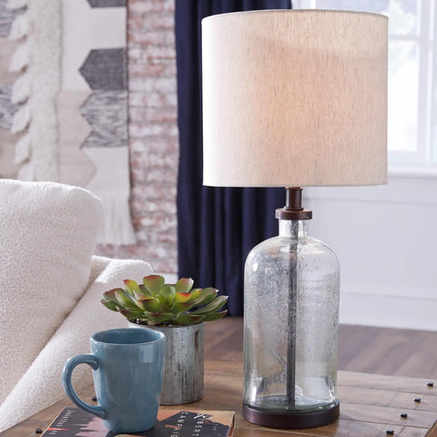 Modern Farmhouse Seeded Glass Table Lamp in Bronze Finish, 22.5 Inch Tall on a wooden table beside a mug and plant