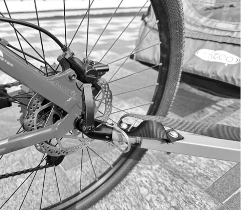 Close-up of angled bike trailer coupler attached to rear wheel of Instep trailer, showcasing durable steel build for universal trailers.