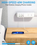 All In One Power Strip Surge Protector With USB C PD, mounted above wooden desk charging phone, 10 wide spacing outlets visible