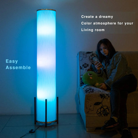 61 Inch RGB LED Floor Lamp With Remote Dimmer And Three Smart Bulbs in living room creating blue ambience next to person on sofa