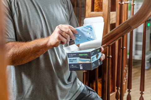 Person holding Granat PRO Fine Profile Sanding Sheets 3x4 Inches with foam backing for contours near wooden stairs