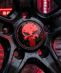 Close-up of Four Pack Red Metal Skull Wheel Center Hub Cap Stickers Self Adhesive Waterproof Rim Covers rugged against a wet surface.