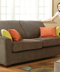 Woman adjusting cushions on a brown sofa with colorful pillows in a bright living room setting
