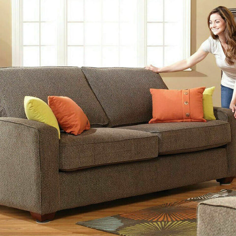 Woman adjusting cushions on a brown sofa with colorful pillows in a bright living room setting