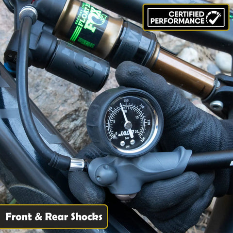 Gloved hand using ShockPro MTB Shock Pump With 300 PSI High Pressure Gauge on mountain bike fork