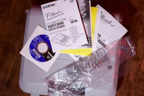 Pro Grade PT 2700 Desktop Labeling System manual with user guide and installation disc on wooden surface