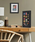 Compact Wall Mounted Pin Display Case Black 15 By 8.5 Inch Collector Showcase Rack holds medals and badges on a desk.