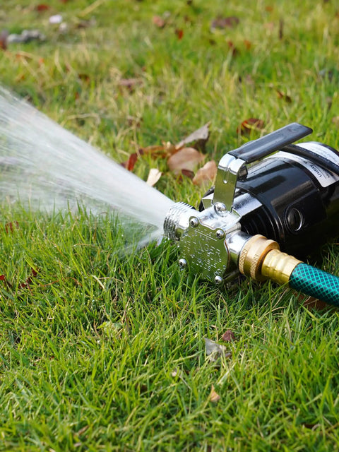 1/10HP Electric Water Transfer Pump With Two 6Ft Garden Hoses spraying water on grass, compact design for yard cleanup.