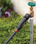 3-In-1 Drip Irrigation Faucet Adapter With Filter, Pressure Regulator And Drip-Lock, attached to outdoor faucet, garden background