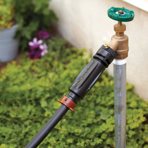 3-In-1 Drip Irrigation Faucet Adapter With Filter, Pressure Regulator And Drip-Lock, attached to outdoor faucet, garden background