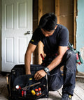 Man reaching into Heavy Duty Tool Bag With 50 Pockets And Large Center Compartment, Multi-Compartment Tool Organizer For Power Tools.