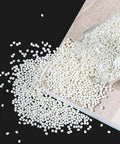 Heavy Duty Hot Melt Edge Banding Adhesive 11 Lb Pellets spilled from a glass jar on a wooden surface.
