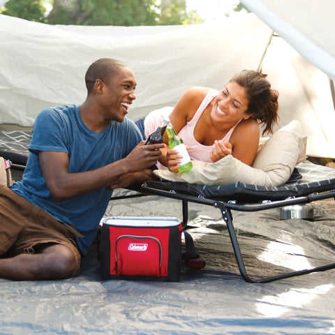 Two campers enjoying drinks on ComfortSmart Big And Tall Camp Cot With Plush Mattress Pad inside a tent.