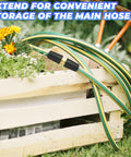 Garden hose with brass connector extending from wooden crate, surrounded by flowers and garden tools.