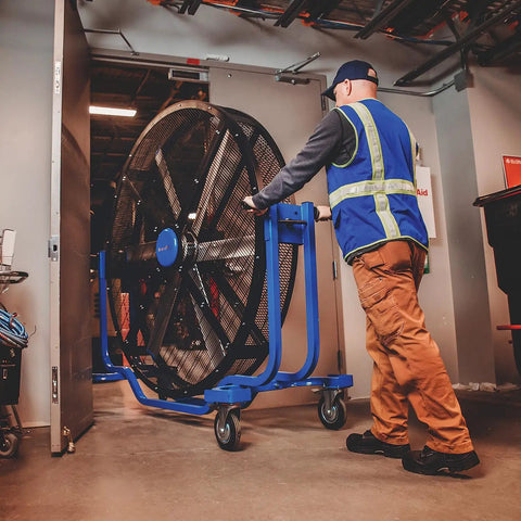 Man moving Six Foot Heavy Duty Mobile Industrial Barrel Fan Pumping Forty Thousand CFM Of Big Air Punch with smooth caster base.