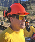 Person wearing Go-To Safety Sunglasses With Polarized Mirror Lenses ANSI Z87 Plus Certified UV 400 Protection, hard hat, and yellow shirt.