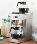 Front view of 12 Cup Commercial Drip Coffee Maker With Glass Carafes And Two Warmers For Cafe Bar Restaurant Office Breakroom Stainless Steel Housing Fast Brew And Pour Over Style Coffee Station For Busy Venues Barista Boss Vibe.