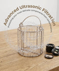 Hella Solid Stainless Steel Ultrasonic Cleaner Basket With Swinging Handle And Fine Mesh Grid Drop Right In For Jewelry Lab Parts Cleaning Bad Boy Universal Fit Heavy Duty Precision Filter Basket Tray on wooden surface with water droplets.