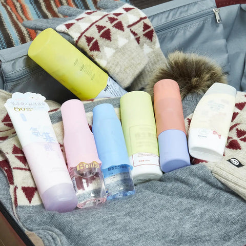 Suitcase with silicone bottle covers 10 pack for travel size toiletries and beach vacay essentials, arranged on clothes