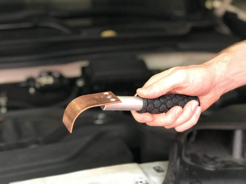 Hand holding curved copper welding spoon from Copper Welding Spoon Set For MIG Spot Welding Three Plate Copper Paddle Backer Kit