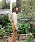Gardener holding a Foldable Spading Fork For Digging And Aerating Durable Steel Garden Tool in a lush home garden setting