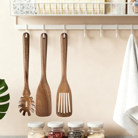 Three Piece Acacia Wood Spatula Set For Cooking, Teethed Pasta Spoon And Spaghetti Fork hanging on hooks in kitchen
