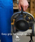 Person holding Velocity Tuned Heat Garage Heater With Fan And Tilt Head, showcasing integrated handle, black color.