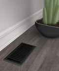 Montezuma Decorative Floor Register 4x10 Black Iron With Durable Damper on wooden floor beside a cactus in a pot