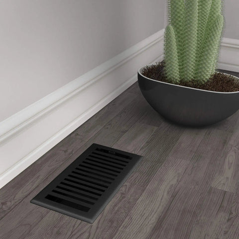 Montezuma Decorative Floor Register 4x10 Black Iron With Durable Damper on wooden floor beside a cactus in a pot